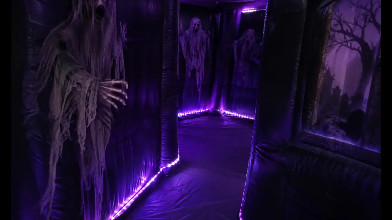 Dark inflatable haunted house walkthrough maze interior with purple LED lighting
